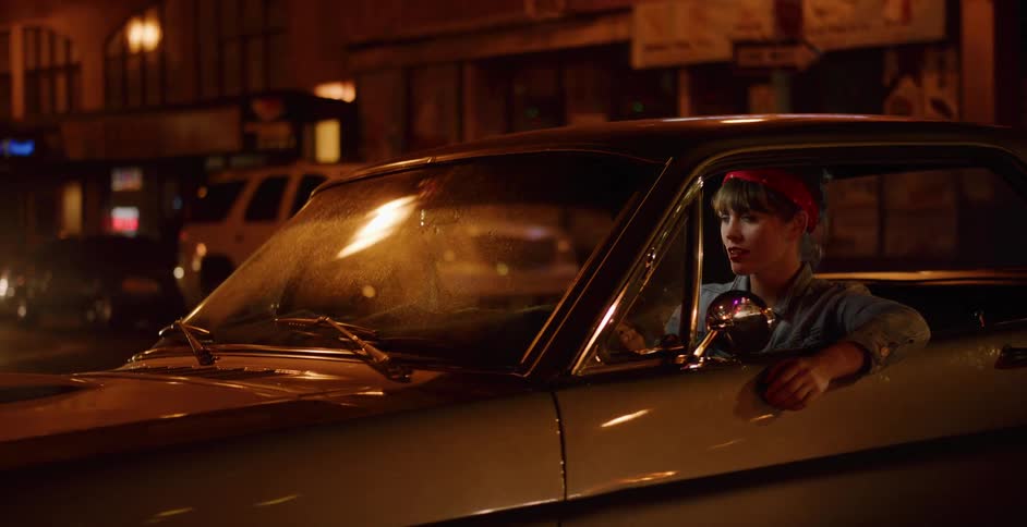 A stylish young woman drives her classic car through the city streets at night