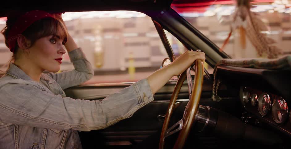 A cool young woman in a denim jacket and red bandana drives her classic convertible car through the neon-lit city streets at night