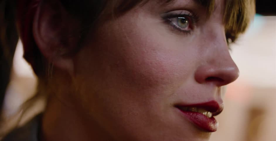 Close-up profile of a thoughtful woman with red lipstick driving through the city at night