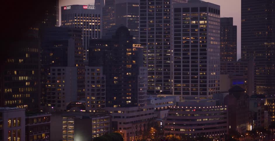 A slow pan reveals the glowing windows of downtown skyscrapers and residential buildings at twilight