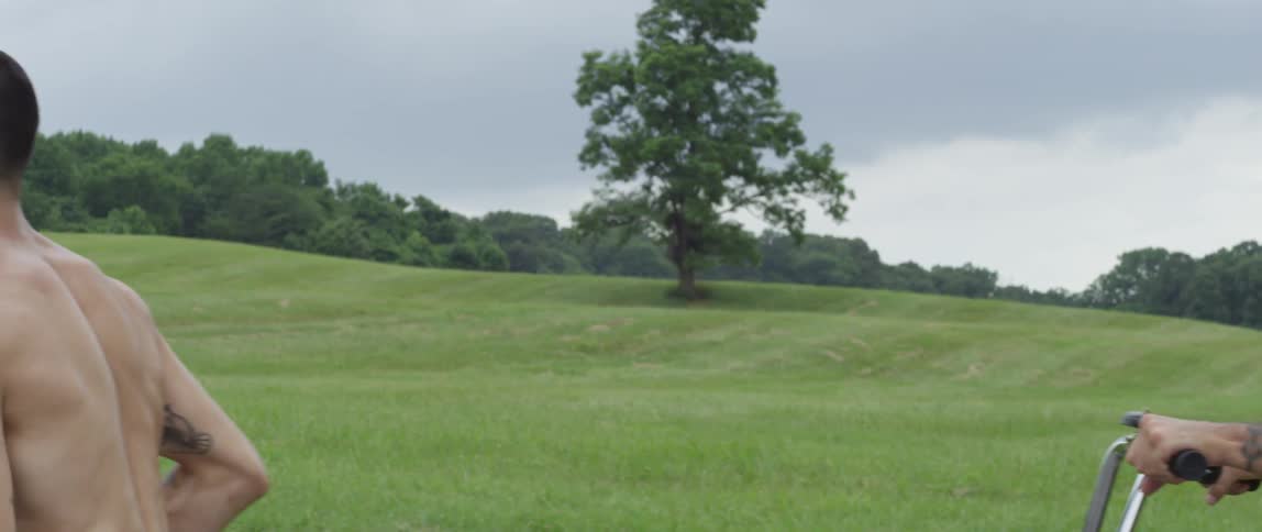 A man rides a bike behind a man jogging during the day