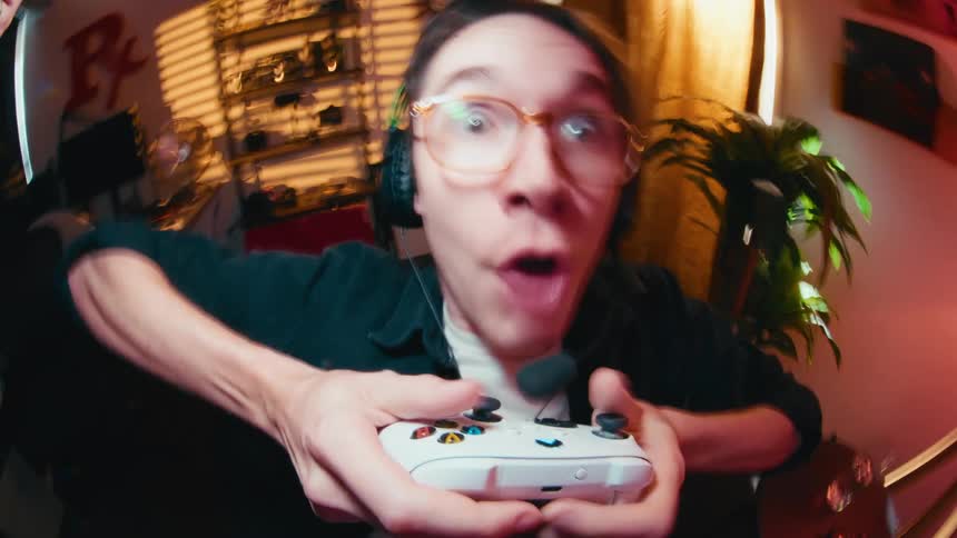A wide-angle, first-person view of an excited gamer with a shocked expression playing intensely with a controller