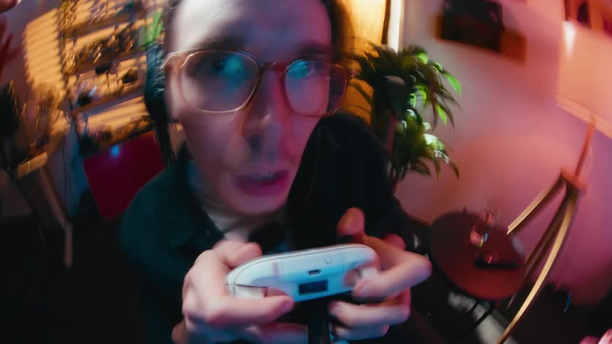 A chaotic, distorted wide-angle shot of a young man with glasses getting intensely excited while playing a video game