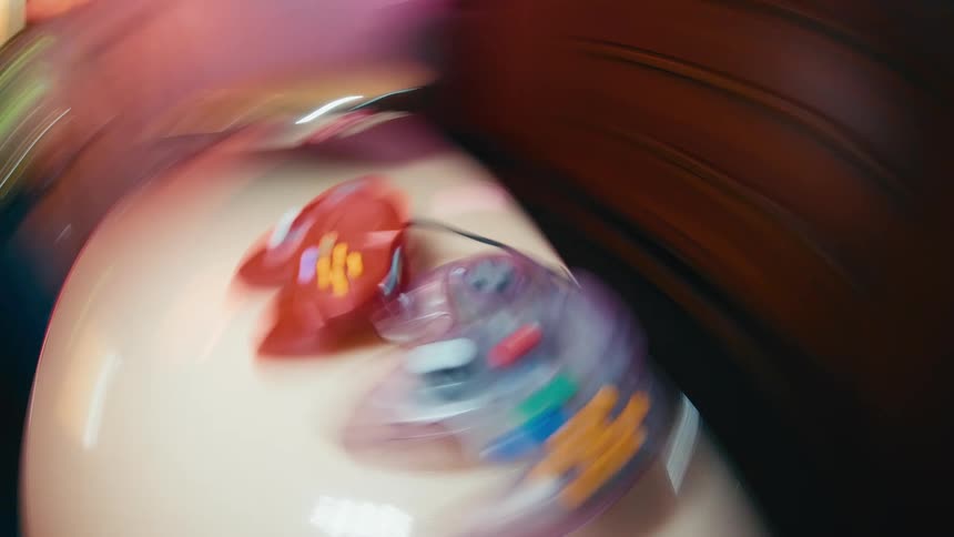 An abstract and disorienting fisheye shot of two retro video game controllers spinning with heavy motion blur