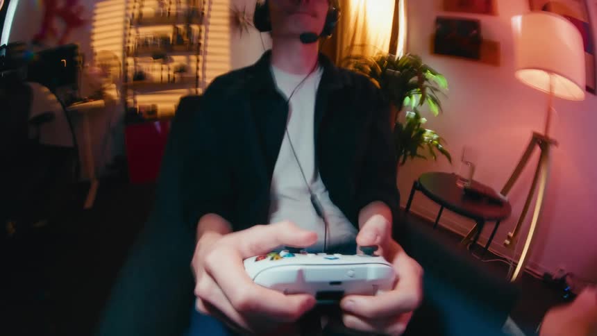 Fast-paced, blurred motion loop of a young gamer intensely playing a video game with a controller, shot on a fisheye lens