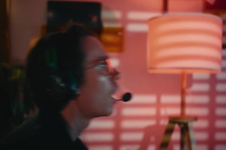 A frustrated gamer with a headset reacts to losing a video game and rubs his temples in disappointment