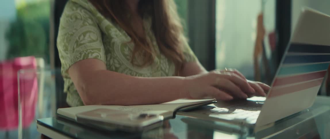 Close-up of a woman's hands typing on a laptop computer before the camera reveals her focused expression