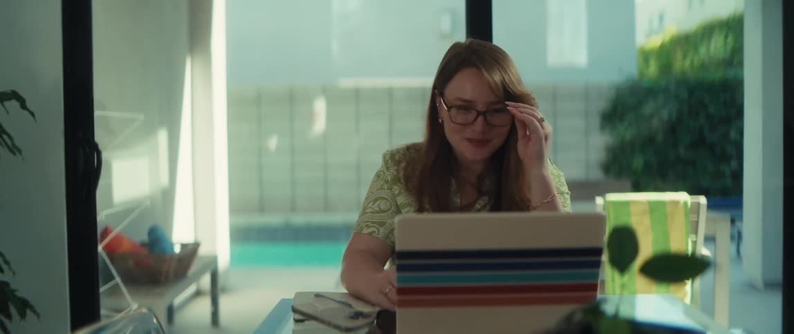 A woman's expression shifts from smiling to crying as she reads something on her laptop in a sunlit room