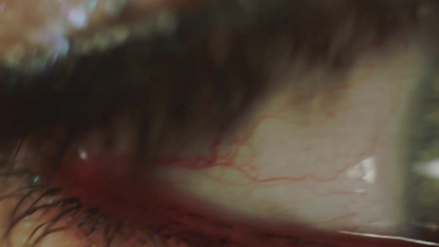 Macro footage reveals the intricate details of a human eye, from sparkling glitter on the eyelid to the delicate blood vessels in the sclera