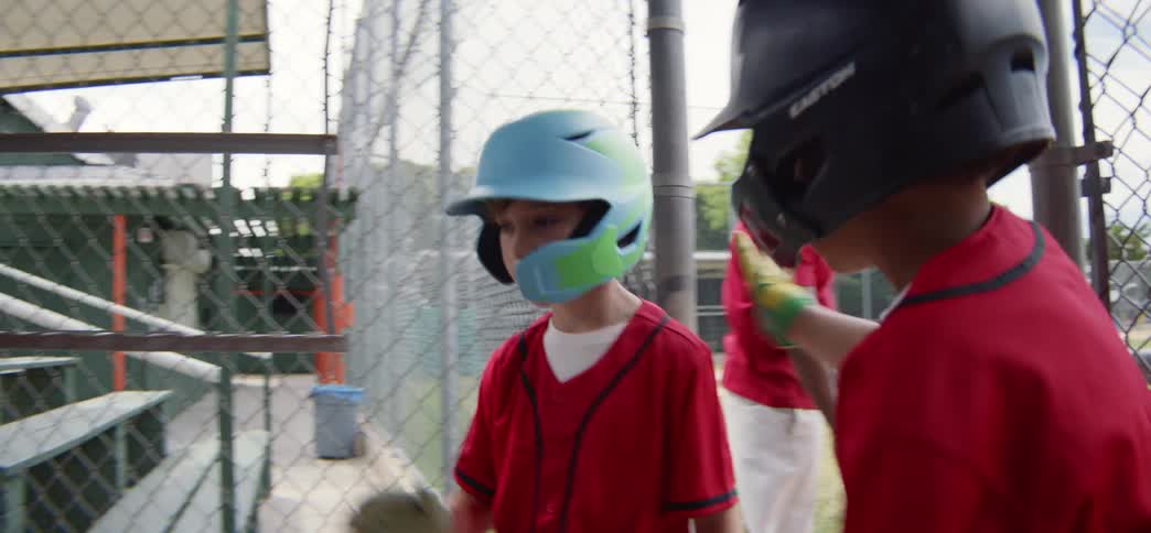 A little league baseball coach gives advice to a young player who then gets encouragement from his teammates in the dugout