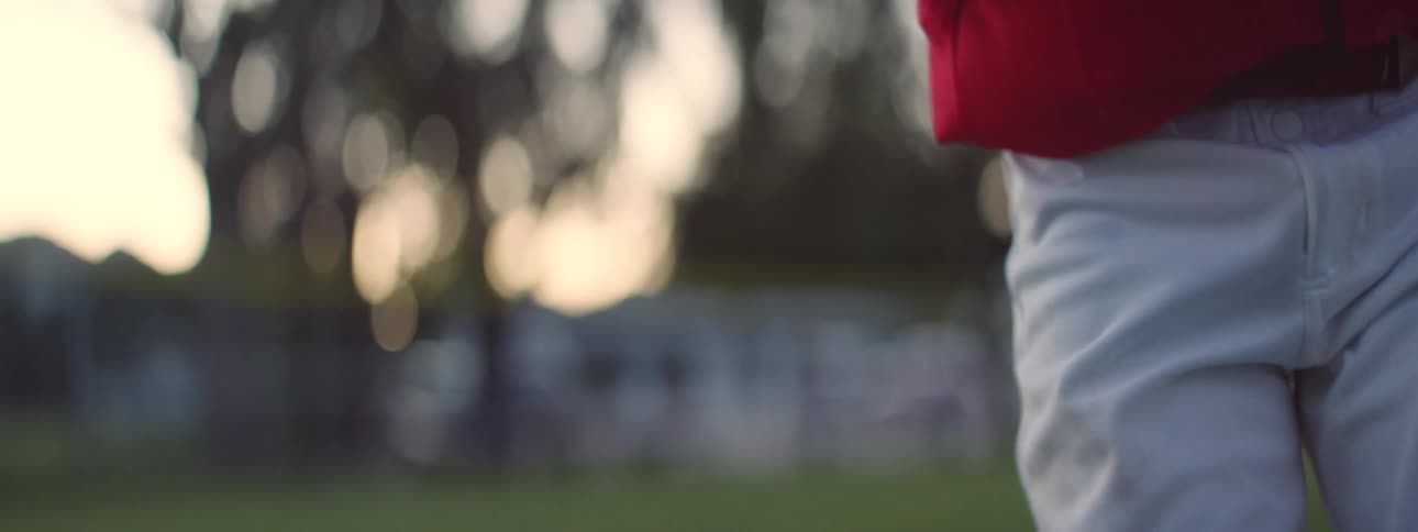 Close-up slow motion shot of a baseball player gripping the ball before throwing a pitch on a green field
