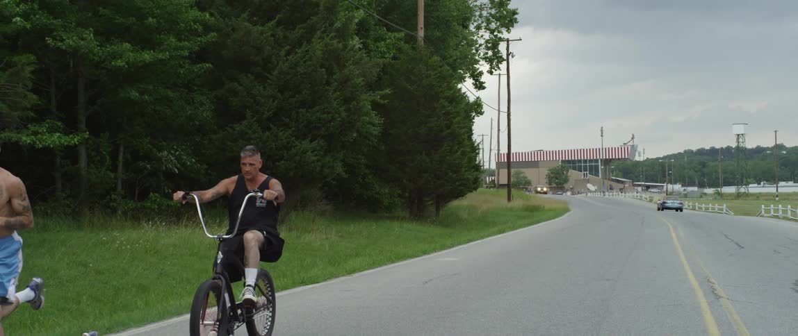 A man jogs while a man ride a bike behind him