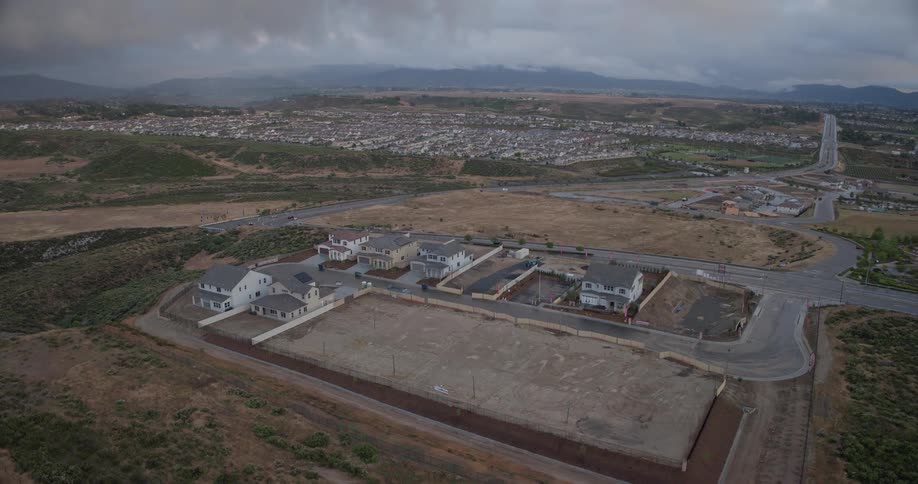 A high-angle time-lapse captures the rapid construction of a new suburban housing development under an overcast sky