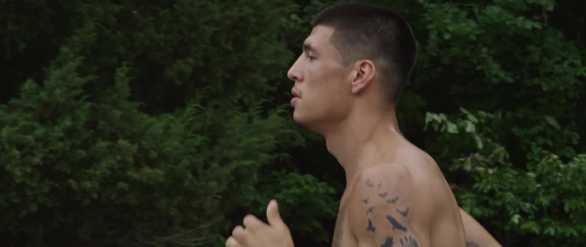 A man with tattoos runs during the day