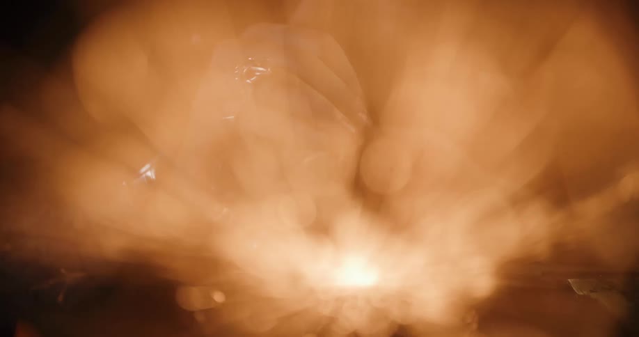 Artistic close-up of a jeweler's hands crafting, with glowing sparks creating a warm, dreamy bokeh effect