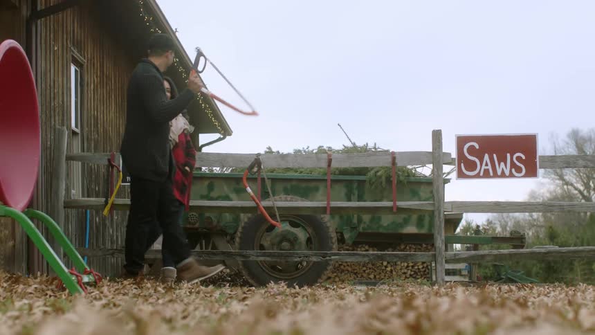 A man and woman pick up a saw in a rural setting