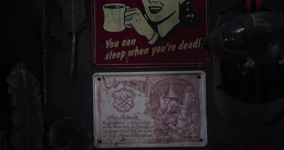 A blacksmith's workshop wall is decorated with vintage signs and handcrafted metal art