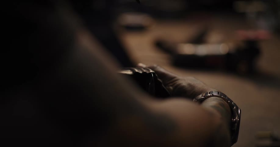 Slow motion close-up of a craftsman's hands hammering and shaping a piece of metal in a workshop