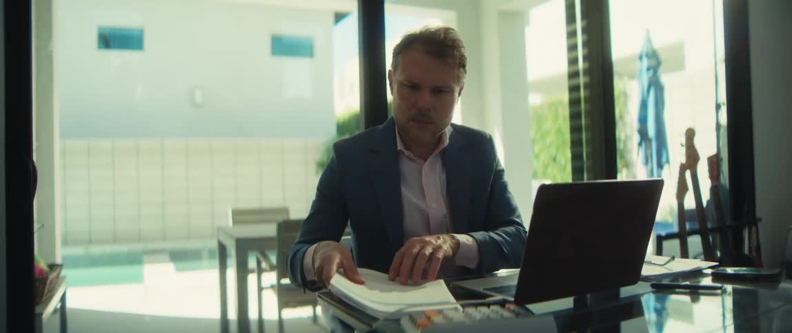 A professional businessman in a suit works from his modern home, analyzing financial charts and data on his laptop
