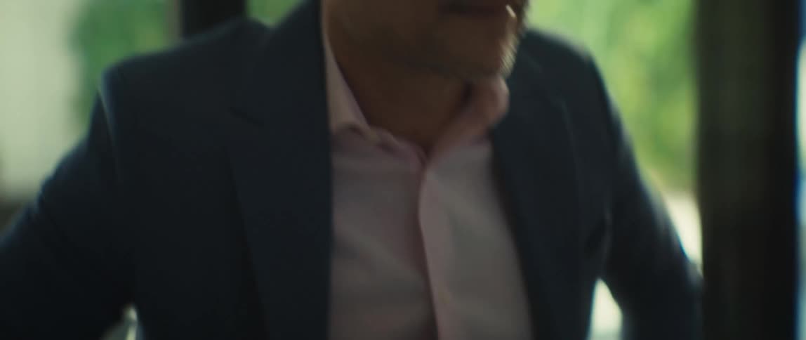 Close-up slow-motion shot of a businessman's hands typing on a laptop, panning up to his focused face