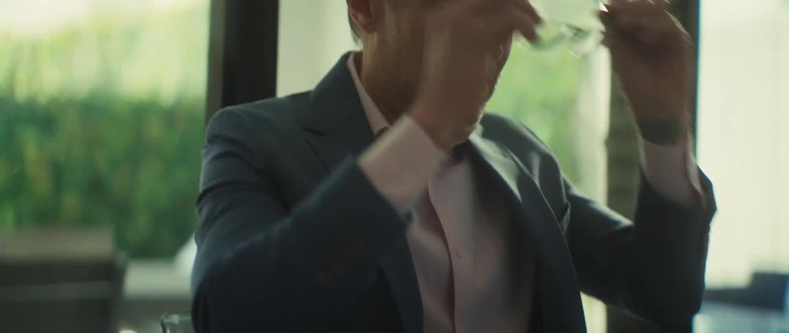 A businessman works diligently on his laptop at a desk, then removes his glasses with a look of satisfaction