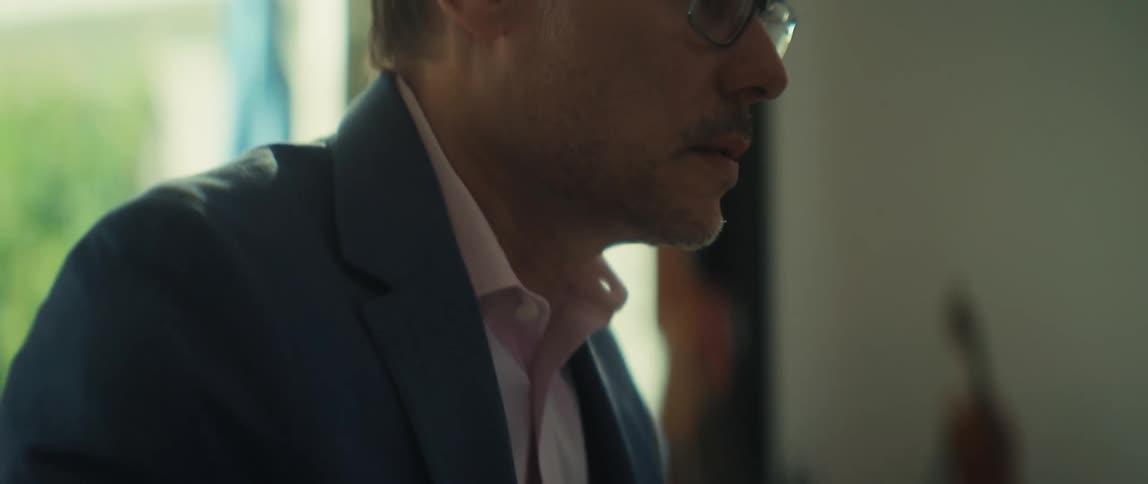 Close-up cinematic shot of a focused businessman in glasses typing on his laptop in a bright office