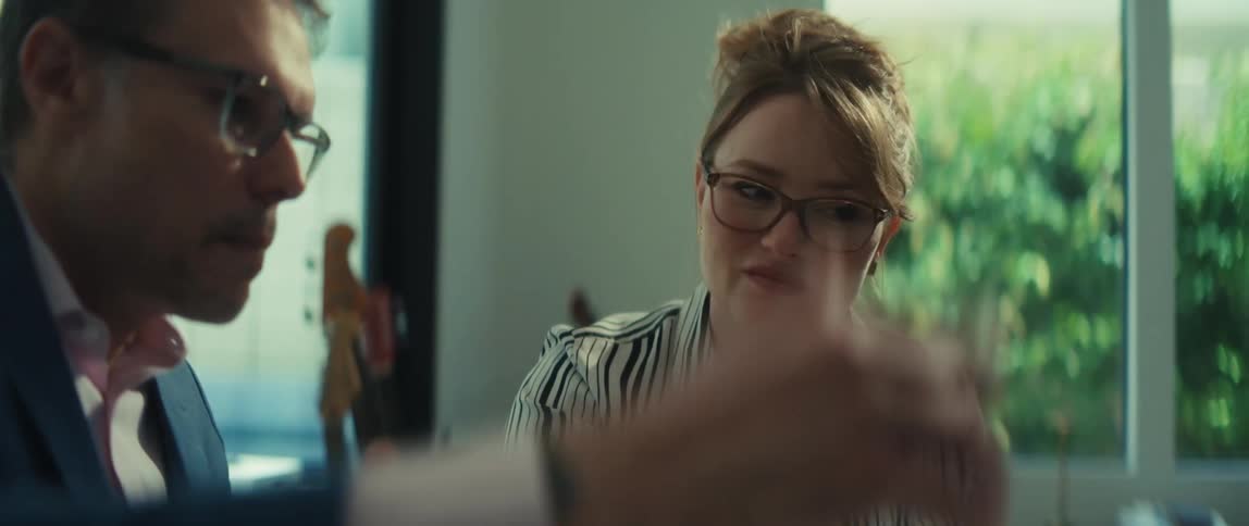 Two colleagues in a modern office intently discuss business plans, gesturing over charts and documents on the desk