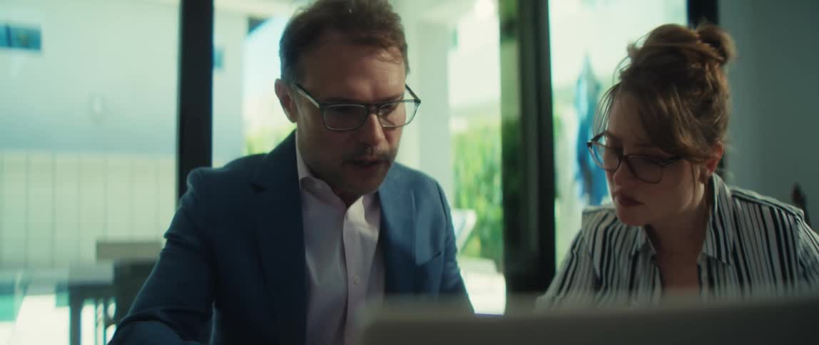 A male manager explains a business report to his female colleague as they work together in a bright, modern office