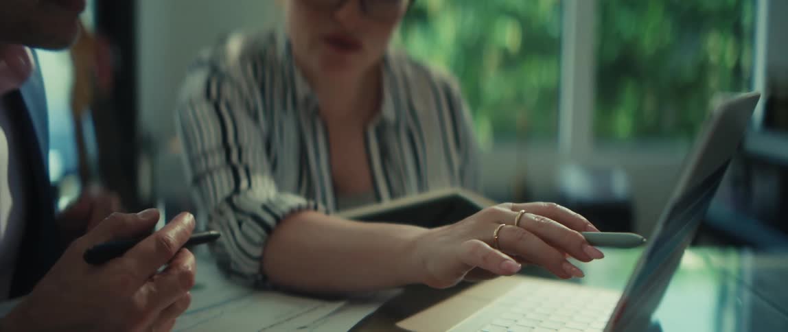 Soft-focus close-up of two business colleagues discussing a project, pointing at a laptop screen during a meeting