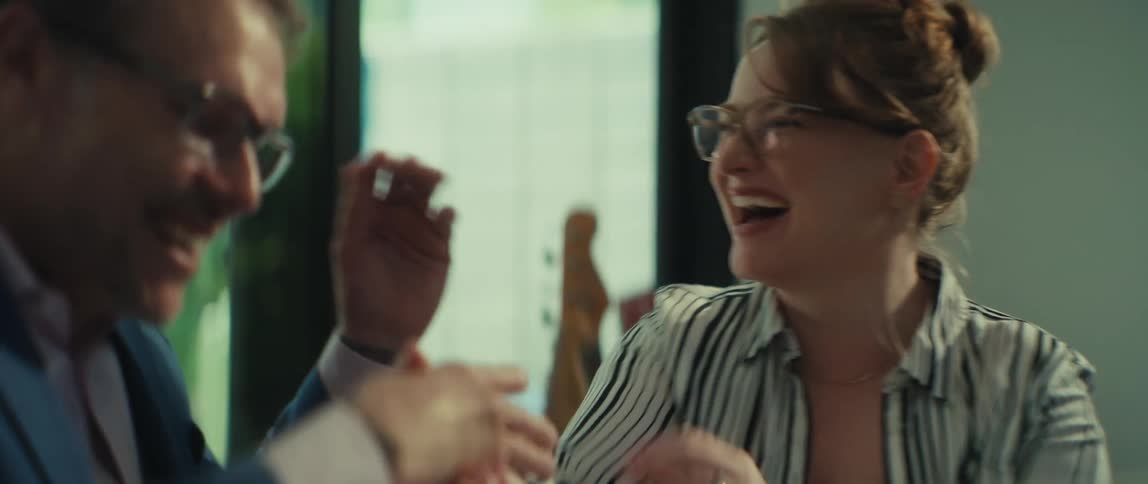 Two business colleagues laugh and shake hands after successfully closing a deal in a modern office