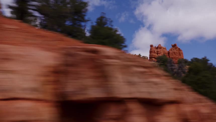 A point-of-view driving shot passes by the beautiful and majestic red rock formations of a canyon in the American Southwest