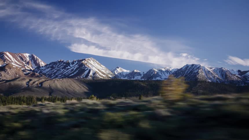 A scenic drive past majestic snow-capped mountains under a beautiful blue sky