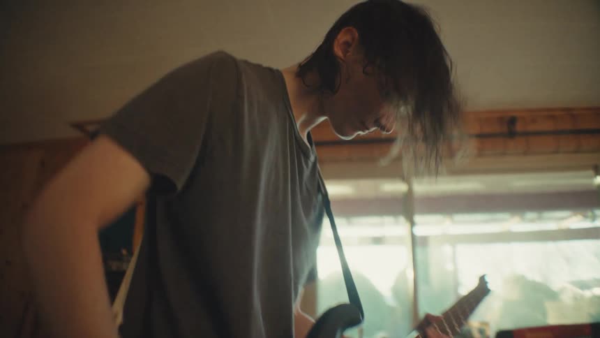 A young female singer and male bassist energetically rehearse their rock music in a cozy living room