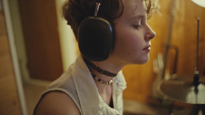 A focused young musician with an alternative style listens to music with their eyes closed in a home studio
