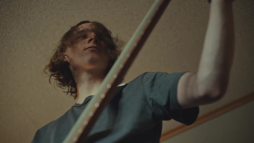 Low angle shot of a young musician intensely playing an electric bass guitar with a pick in slow motion