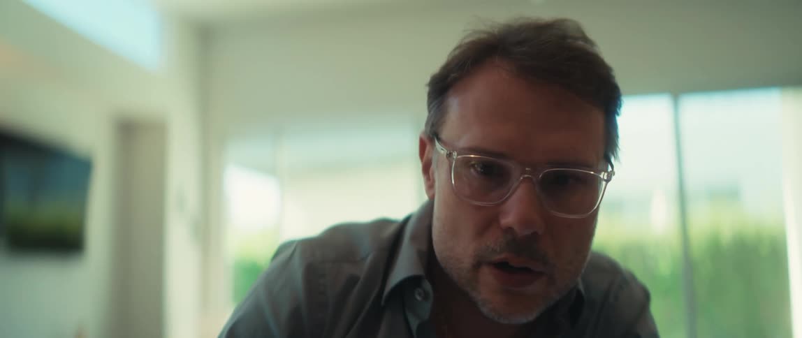 A slow focus pull reveals a businessman in glasses intensely discussing a financial report with bar graphs