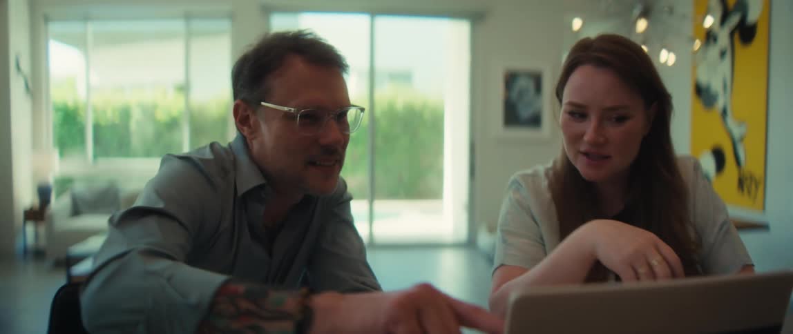 A man and woman collaborate on a laptop, pointing at the screen and discussing a project in a bright modern home office