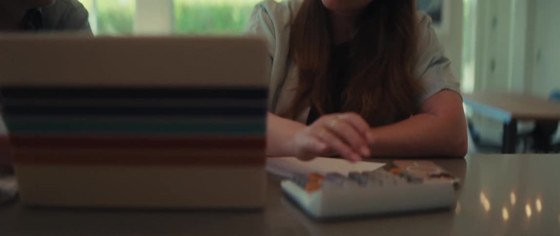 A man reviews financial documents while a woman uses a calculator as they work on their budget at the dining room table