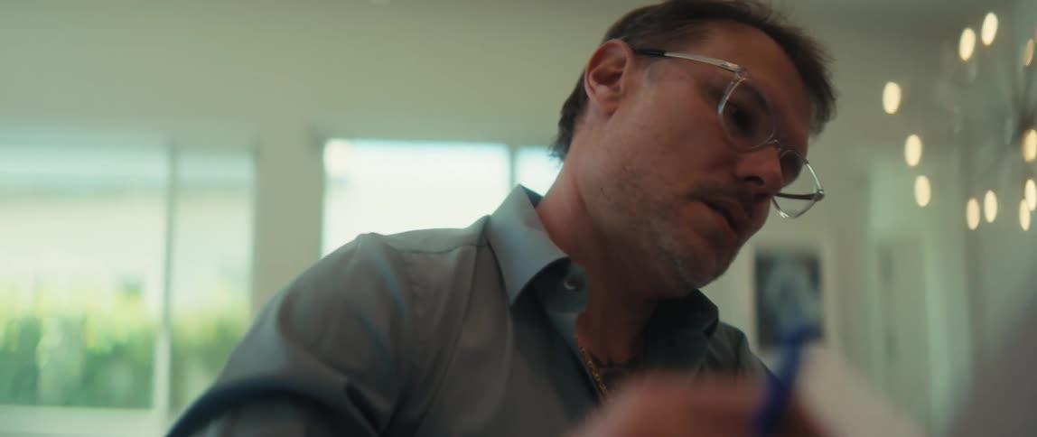A tattooed man wearing glasses collaborates with a woman, analyzing charts and documents at a modern desk