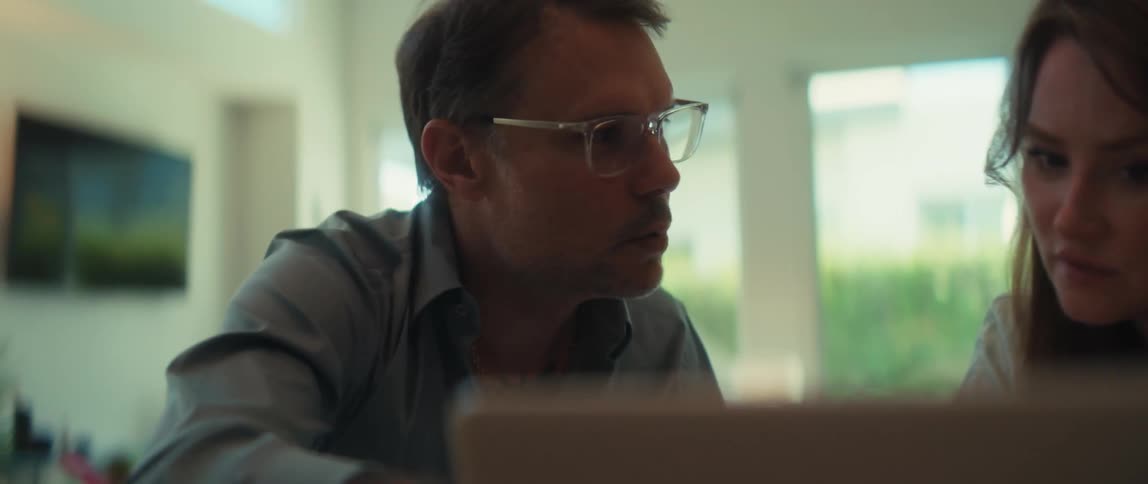 A focused businessman with glasses explains a project on a laptop to his female colleague in a modern office