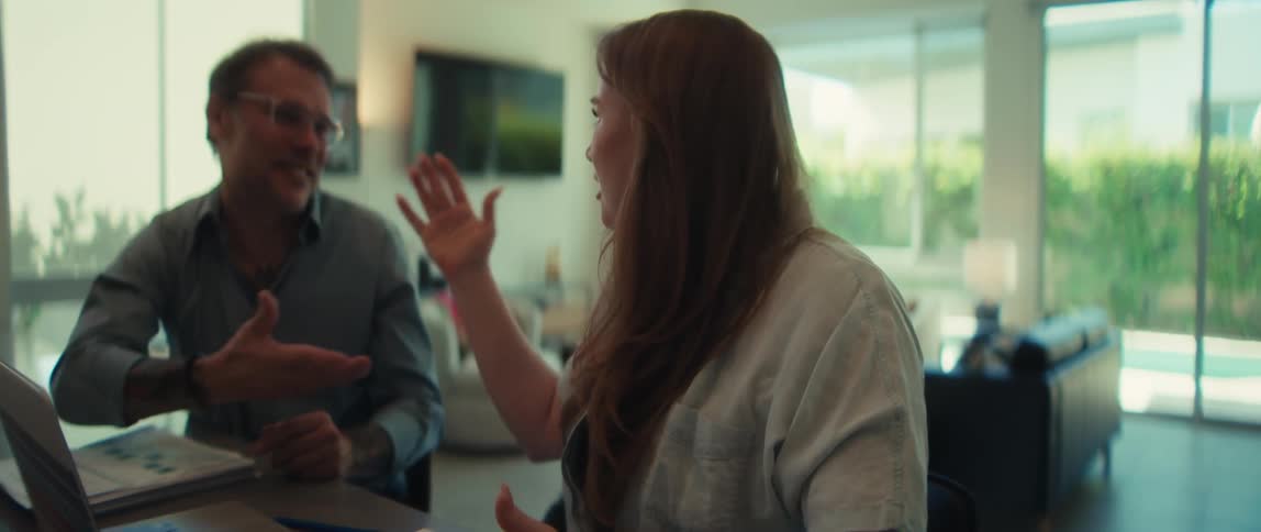 A happy couple collaborates on their budget at home, using a laptop and calculator, and celebrates their financial success together in slow motion