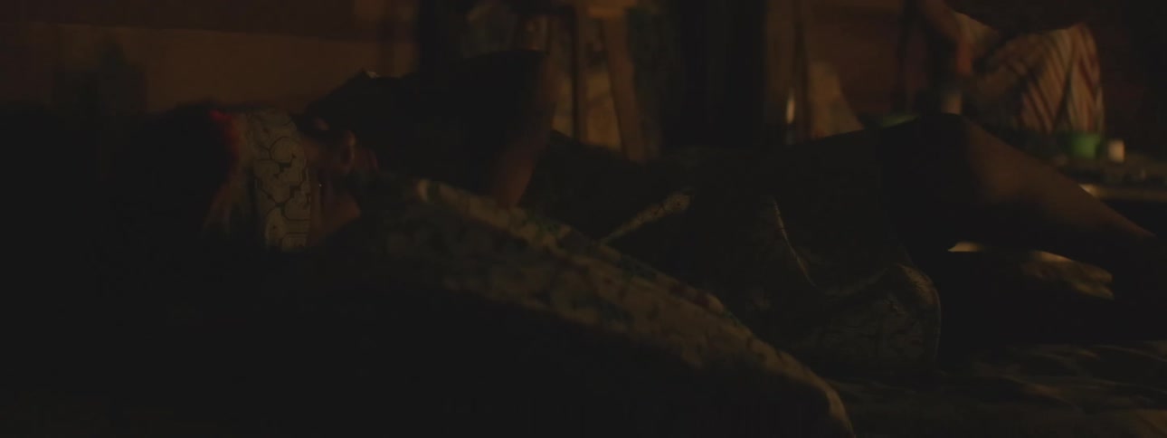 A person wearing a patterned sleep mask rests peacefully in a dark room