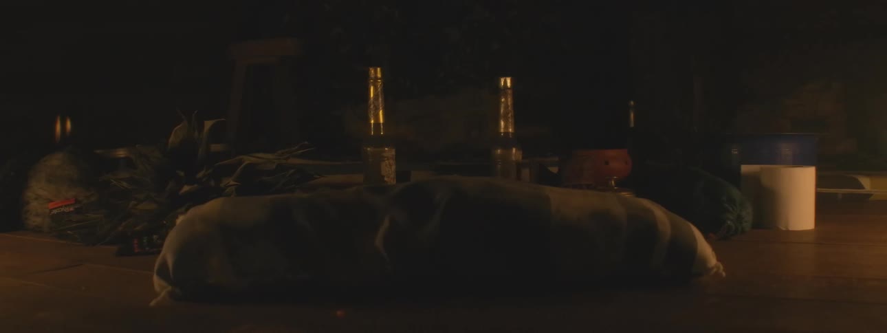 Two mysterious bottles sit on a table outside at night as smoke rises into the darkness
