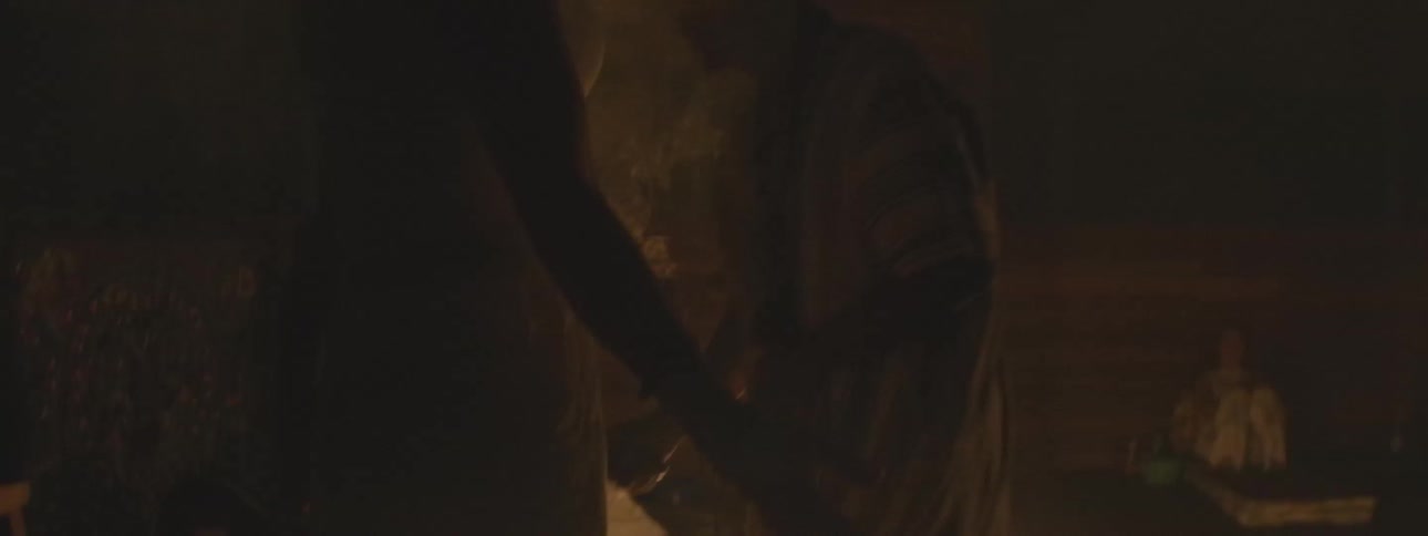 A shaman performs a mystical healing ritual with smoke and fire in a dark, candlelit room