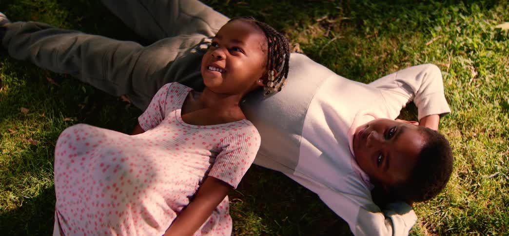 Overhead shot of a happy young brother and sister relaxing together while lying on the grass in the sun