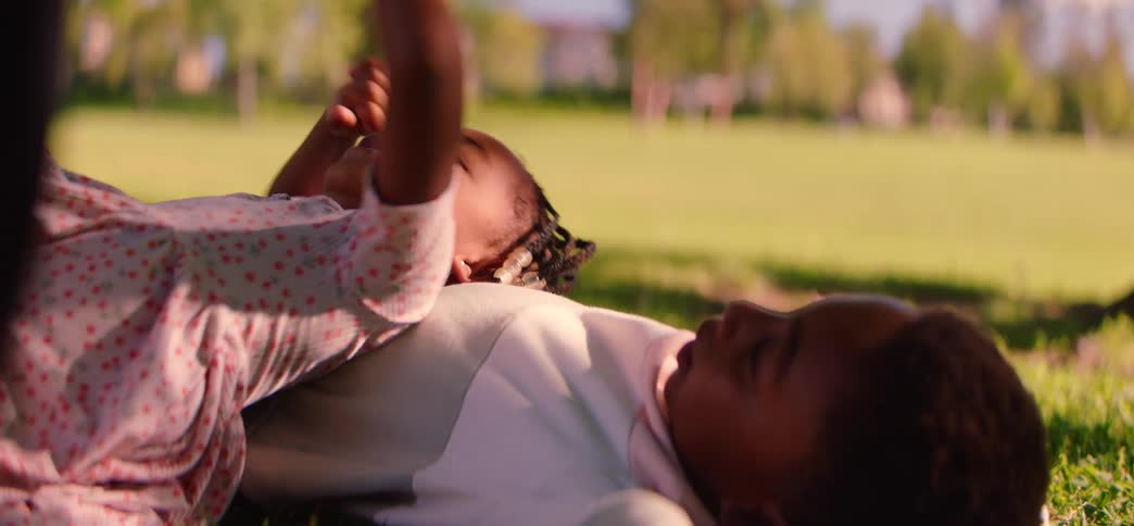 Adorable young brother and sister lie on the grass together, enjoying a peaceful, sunny day in the park