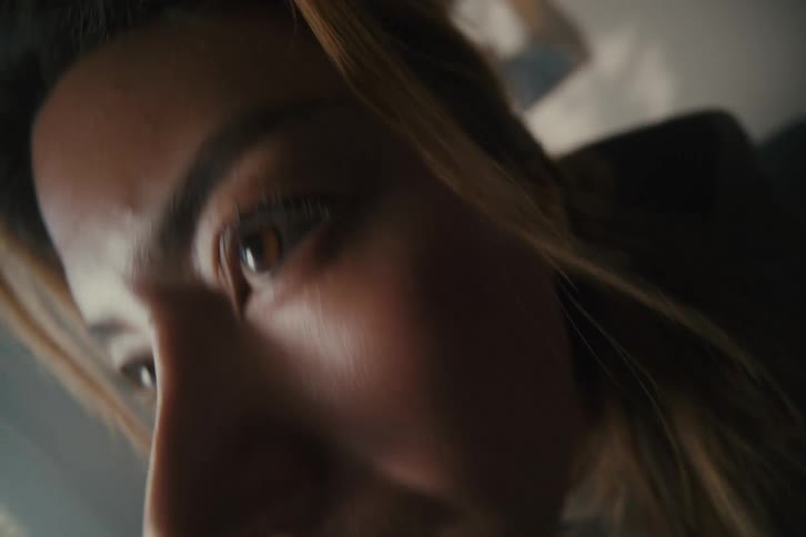 A determined young woman works on an electronics project, the camera focusing from the circuit board to her concentrated expression