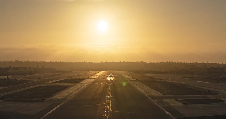 Busy airport runway timelapse shows planes taking off and landing against a beautiful golden hour sunset