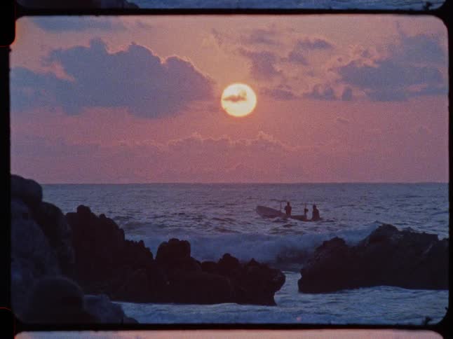 Vintage film captures a small boat with people on the ocean waves against a stunning pink sunset