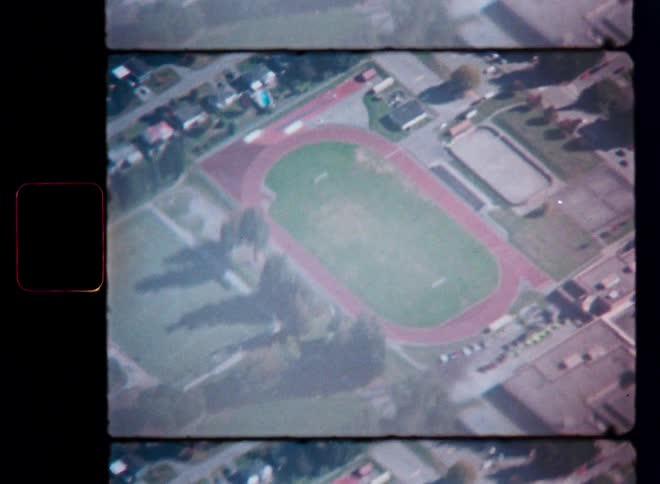 Vintage 8mm aerial footage captures a bird's-eye view of a high school running track and football field